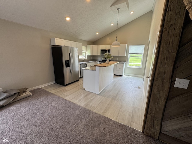 kitchen with high vaulted ceiling, stainless steel appliances, baseboards, white cabinetry, and a kitchen island
