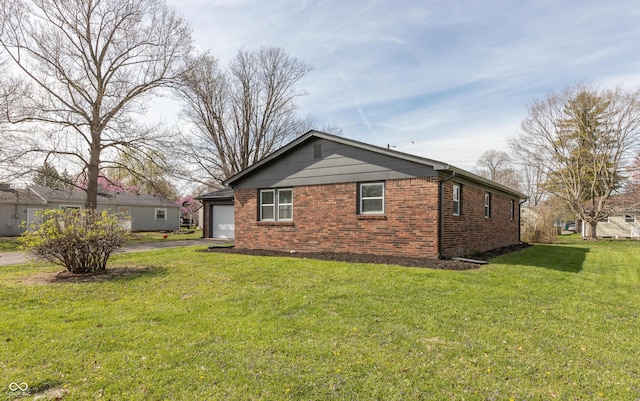 back of house featuring aphalt driveway, brick siding, and a yard