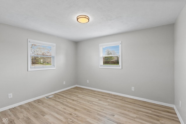 spare room featuring plenty of natural light, visible vents, and light wood-type flooring