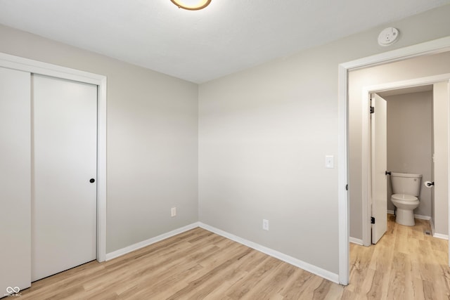 unfurnished bedroom with baseboards, light wood-style floors, and a closet