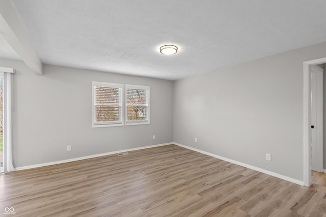 empty room featuring light wood-style floors, a healthy amount of sunlight, and baseboards