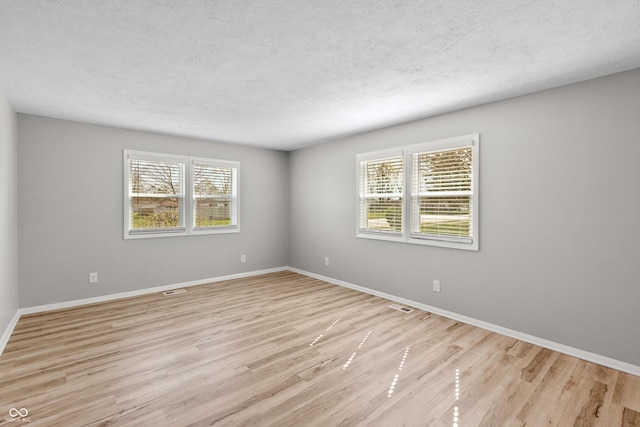 unfurnished room featuring light wood-style flooring, baseboards, and a healthy amount of sunlight