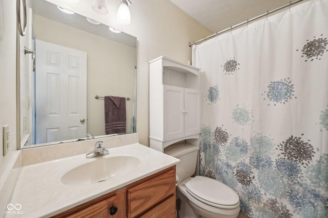 bathroom featuring toilet, vanity, and curtained shower