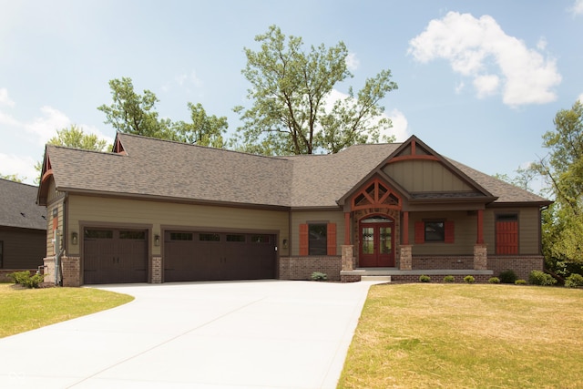 craftsman house featuring driveway, french doors, a front yard, brick siding, and an attached garage