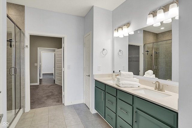 bathroom with a walk in closet, tile patterned floors, a stall shower, and a sink