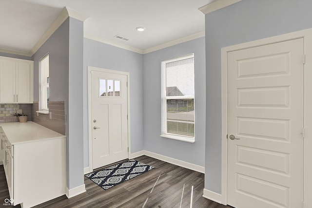 entryway with visible vents, baseboards, dark wood-type flooring, and crown molding