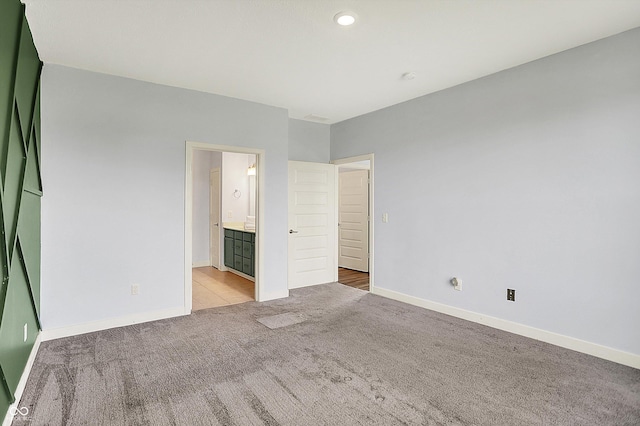 unfurnished bedroom with carpet floors, ensuite bath, and baseboards