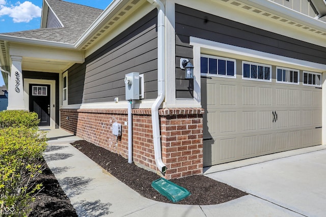 view of property exterior with a garage, brick siding, a shingled roof, and driveway