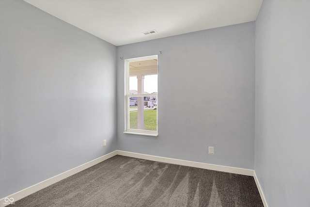 unfurnished room featuring baseboards, dark colored carpet, and visible vents