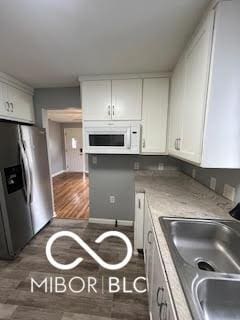 517 Dicks St, Lebanon, IN 46052 - kitchen with white microwave, a sink, white cabinets, and stainless steel refrigerator with ice dispenser