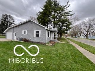 517 Dicks St, Lebanon, IN 46052 - view of side of property with concrete driveway, an attached garage, and a lawn
