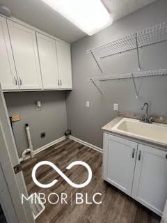 517 Dicks St, Lebanon, IN 46052 - laundry area with a sink, baseboards, cabinet space, and dark wood-style flooring