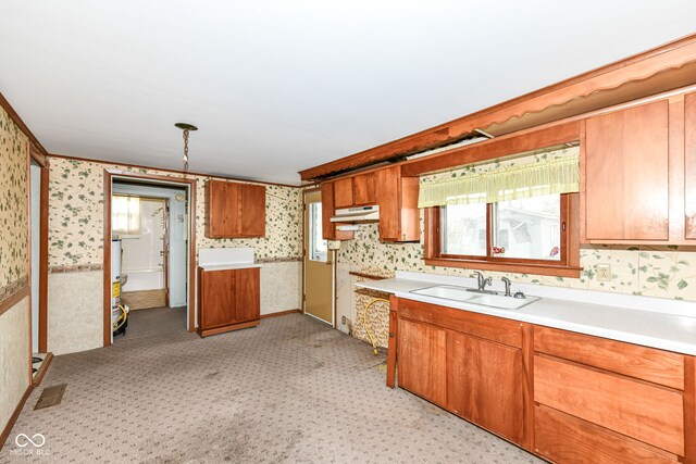 2001 S I St, Elwood, IN 46036 - kitchen featuring wallpapered walls, under cabinet range hood, light countertops, a sink, and brown cabinetry