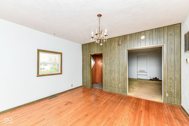 2001 S I St, Elwood, IN 46036 - spare room featuring wooden walls, visible vents, baseboards, a chandelier, and hardwood / wood-style flooring