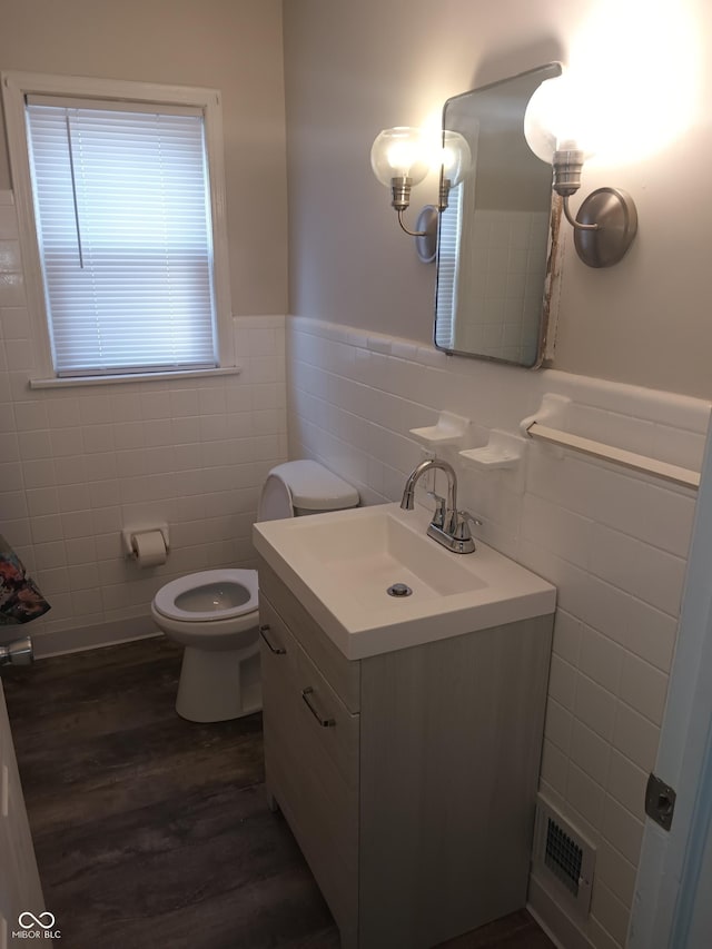 bathroom featuring visible vents, a wainscoted wall, toilet, wood finished floors, and tile walls