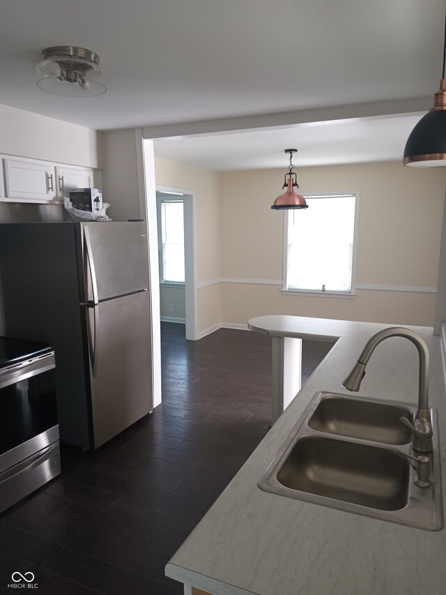kitchen with baseboards, a sink, dark wood-style floors, white cabinetry, and stainless steel appliances
