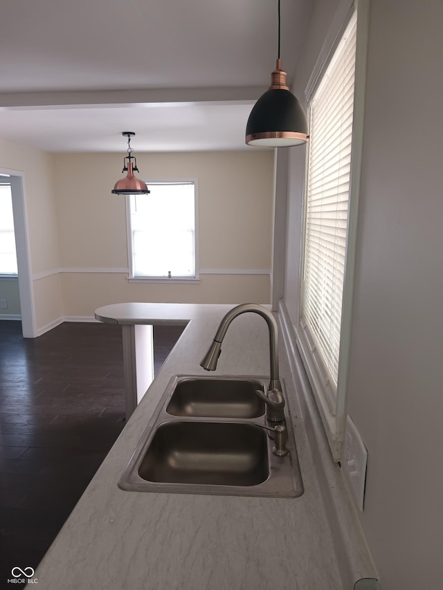 kitchen featuring decorative light fixtures, dark wood-style flooring, baseboards, and a sink