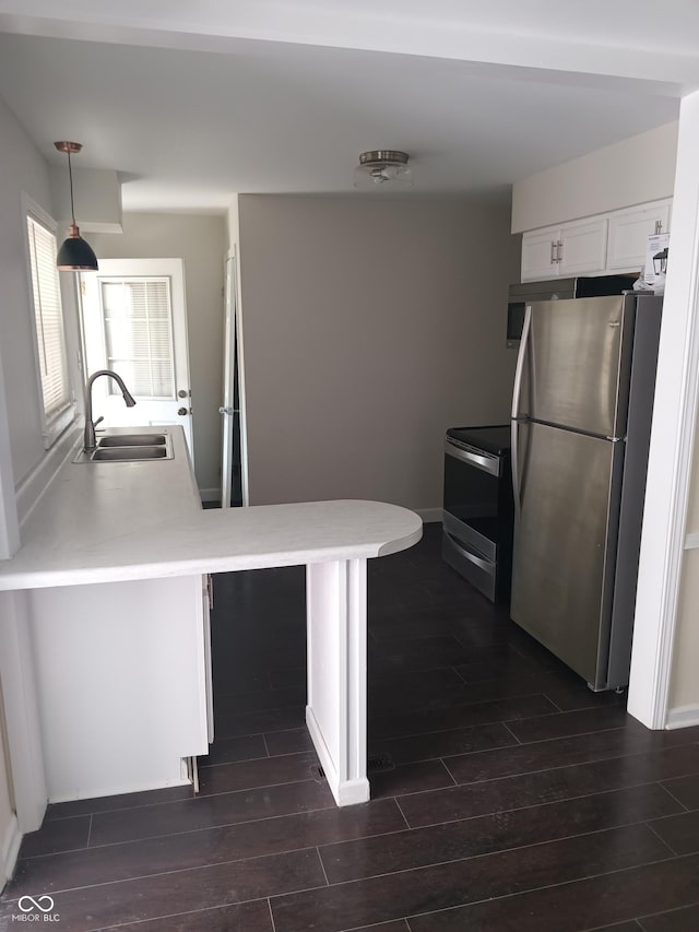 kitchen with white cabinetry, light countertops, a sink, stainless steel appliances, and dark wood-style floors