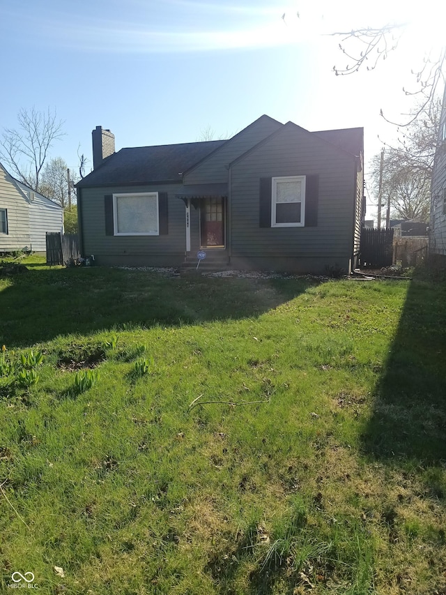 view of front of house with a chimney, fence, and a front lawn