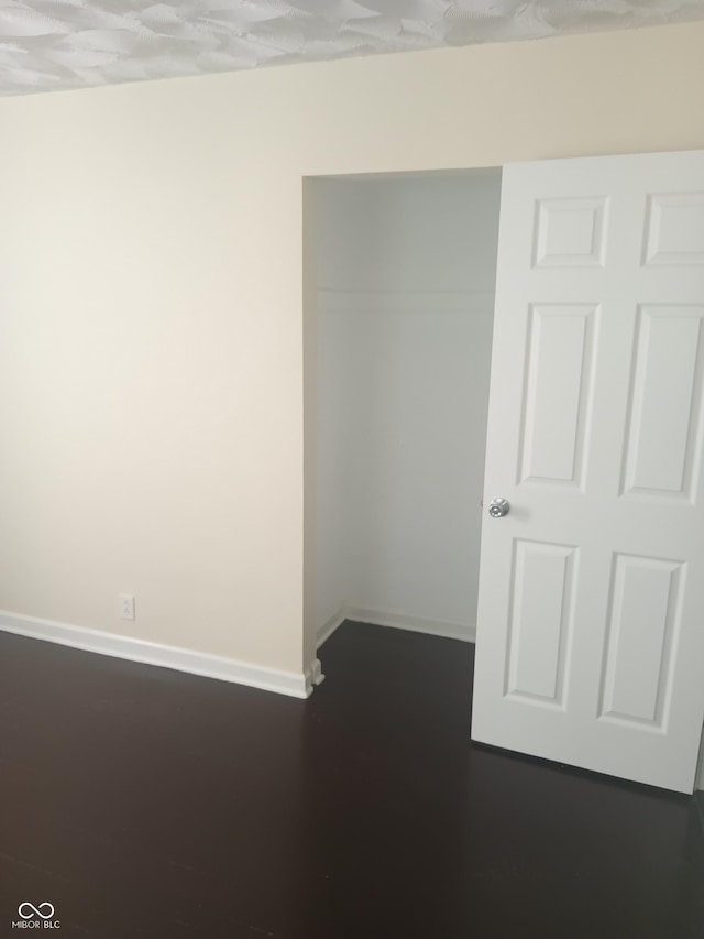 empty room featuring baseboards and dark wood-style floors