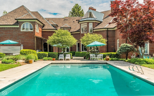 290 Breakwater Dr, Fishers, IN 46037 - rear view of house featuring an outdoor pool, a standing seam roof, a chimney, a patio, and brick siding