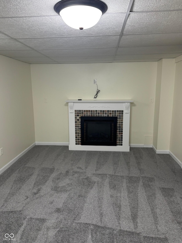interior space featuring carpet floors, baseboards, a paneled ceiling, and a tile fireplace