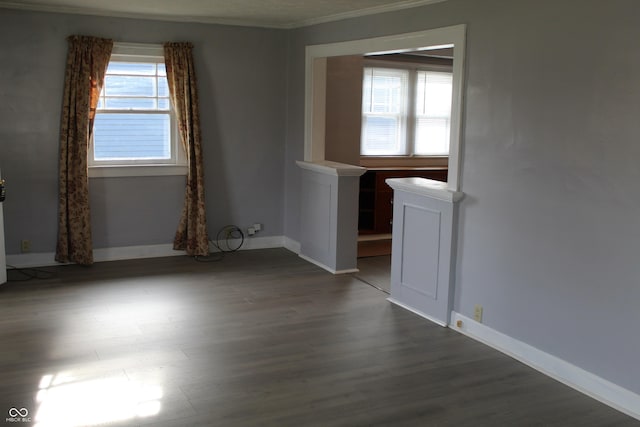 spare room featuring crown molding, dark wood-type flooring, and plenty of natural light