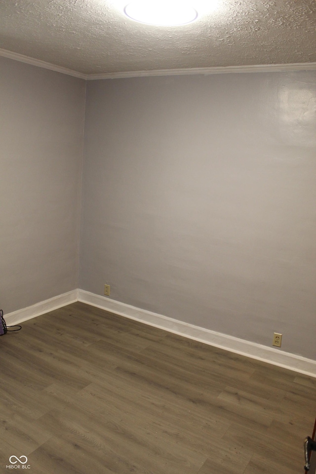 unfurnished room featuring dark wood finished floors, a textured ceiling, baseboards, and ornamental molding
