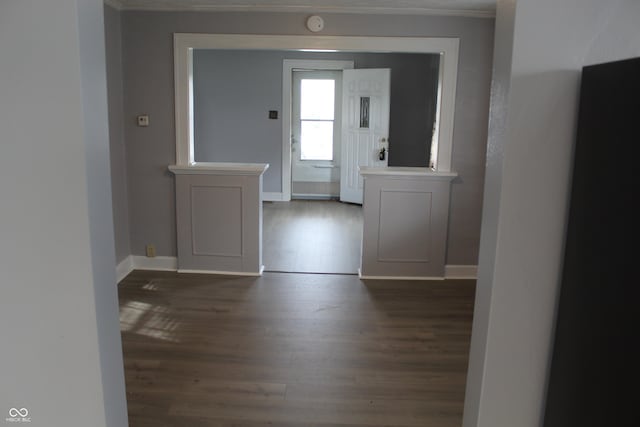 interior space with baseboards, ornamental molding, and dark wood-type flooring