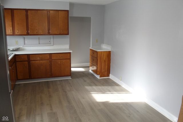 kitchen with brown cabinetry, baseboards, wood finished floors, and light countertops
