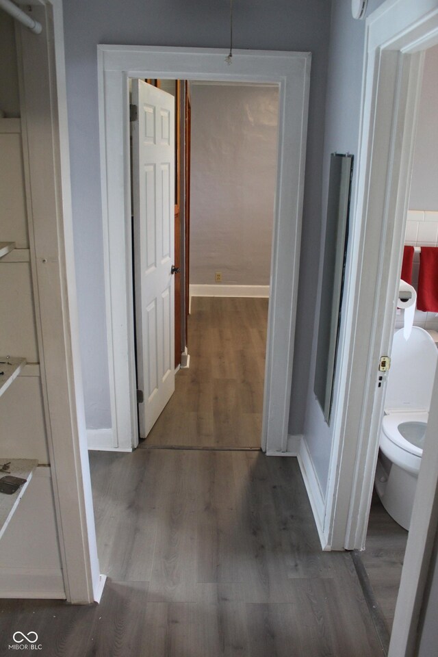 corridor featuring baseboards and wood finished floors