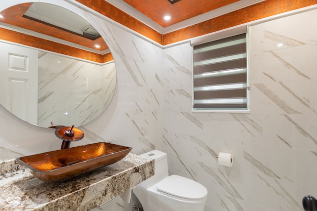 half bathroom with a sink, tile walls, and toilet