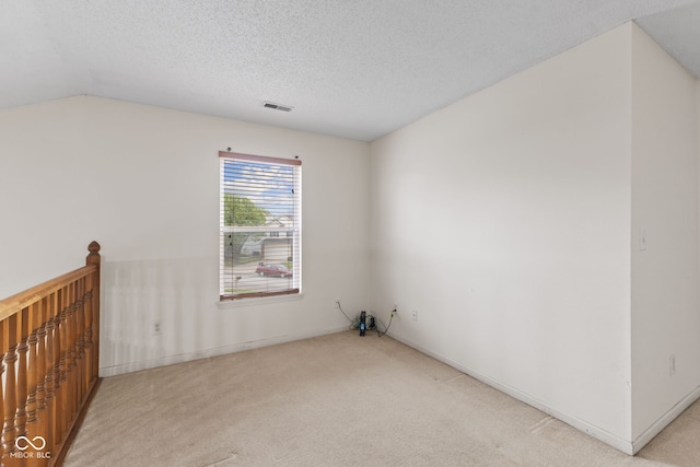 empty room featuring a textured ceiling, visible vents, light carpet, and baseboards