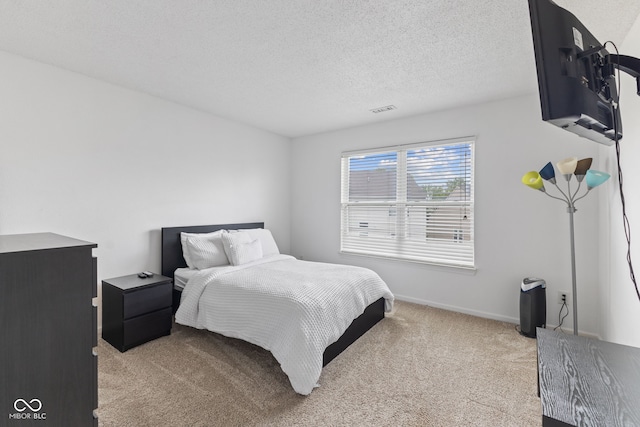 bedroom with carpet floors, a textured ceiling, visible vents, and baseboards
