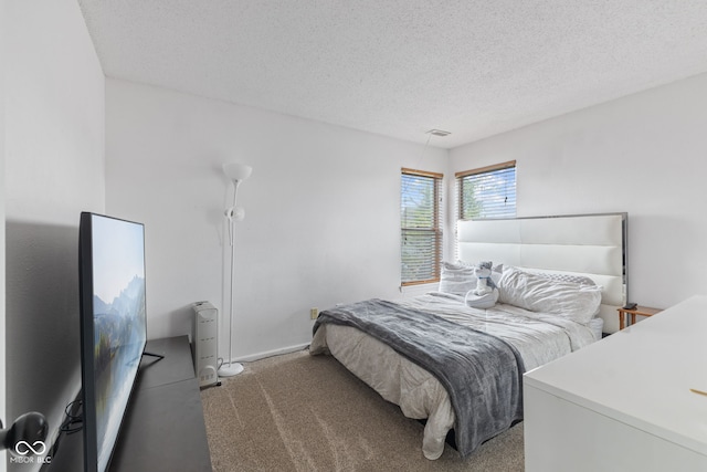carpeted bedroom featuring baseboards, a textured ceiling, and visible vents