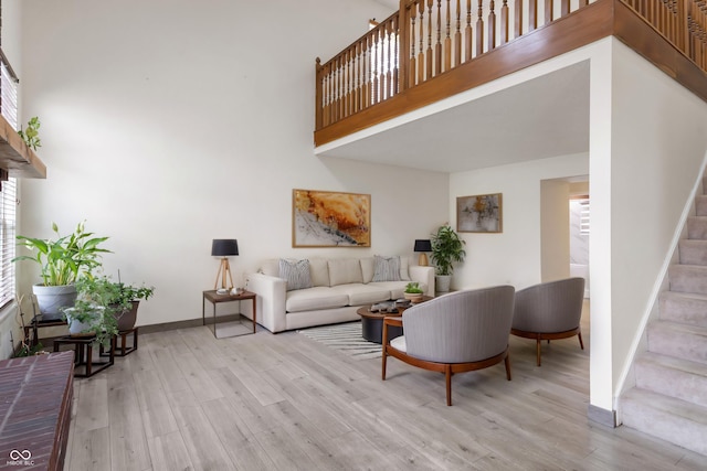 living room featuring baseboards, a high ceiling, stairs, and wood finished floors