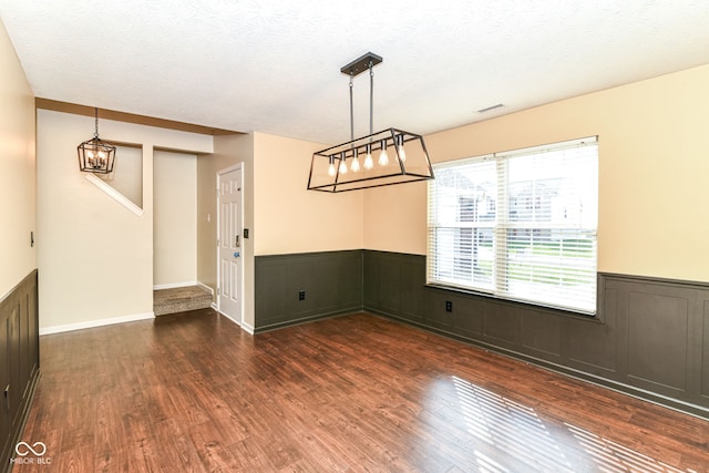 6479 Enclave Blvd, Greenwood, IN 46143 - unfurnished dining area with dark wood-style flooring, a wainscoted wall, a chandelier, and a textured ceiling