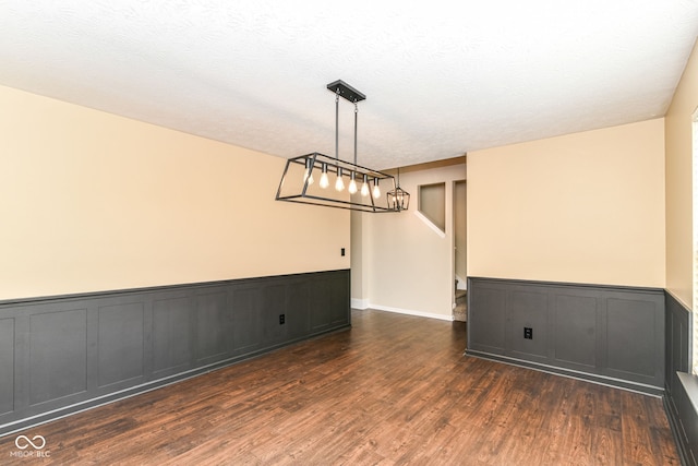 6479 Enclave Blvd, Greenwood, IN 46143 - empty room with dark wood finished floors, wainscoting, a decorative wall, and a textured ceiling