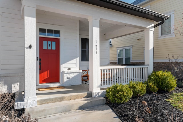 entrance to property featuring covered porch and brick siding