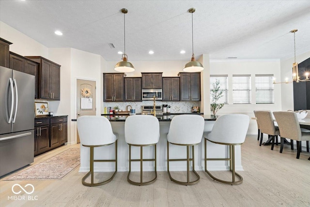 1614 Waterleaf Dr, Westfield, IN 46074 - kitchen with appliances with stainless steel finishes, light wood-type flooring, a kitchen bar, dark countertops, and dark brown cabinets