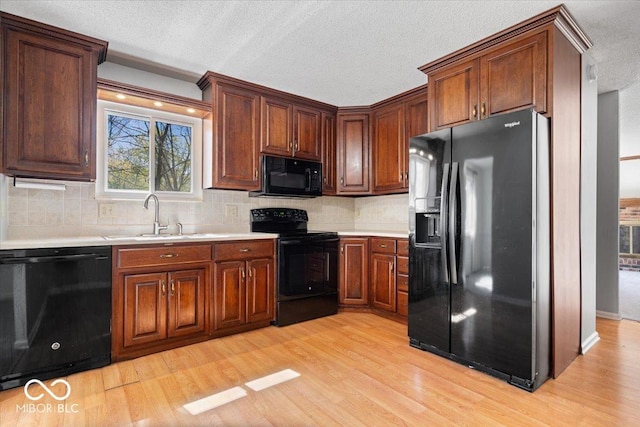 315 Heritage Ct, Fishers, IN 46038 - kitchen featuring a textured ceiling, a sink, black appliances, light wood finished floors, and light countertops