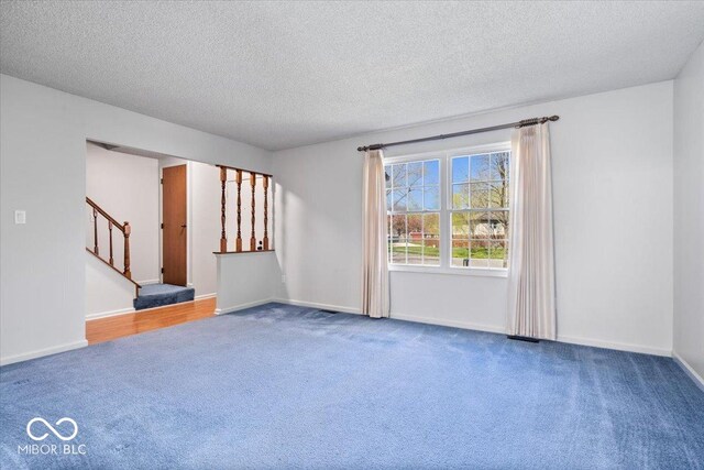 315 Heritage Ct, Fishers, IN 46038 - unfurnished room with a textured ceiling, baseboards, carpet floors, and stairs