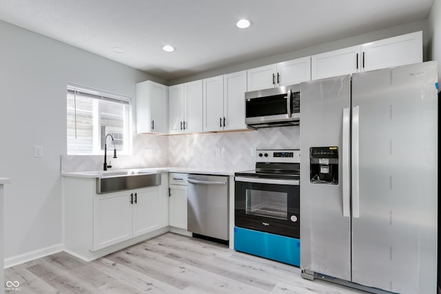 1125 N Colorado Ave, Indianapolis, IN 46201 - kitchen with tasteful backsplash, a sink, stainless steel appliances, light wood finished floors, and white cabinets