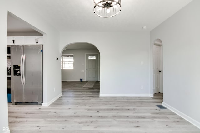 1125 N Colorado Ave, Indianapolis, IN 46201 - unfurnished dining area with arched walkways, baseboards, light wood finished floors, and visible vents