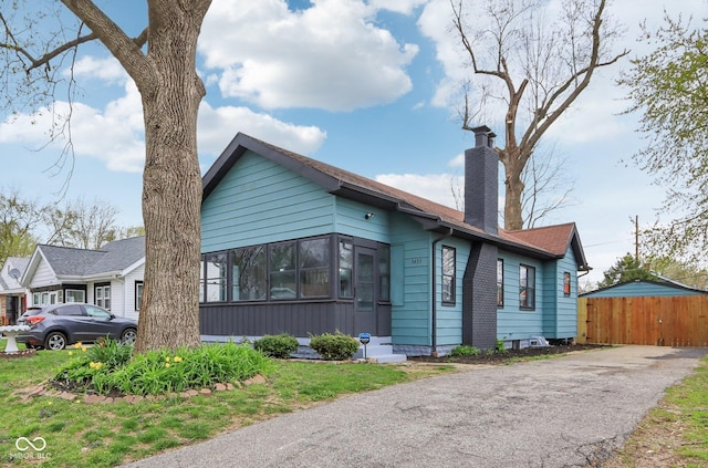 bungalow-style home featuring fence and a chimney