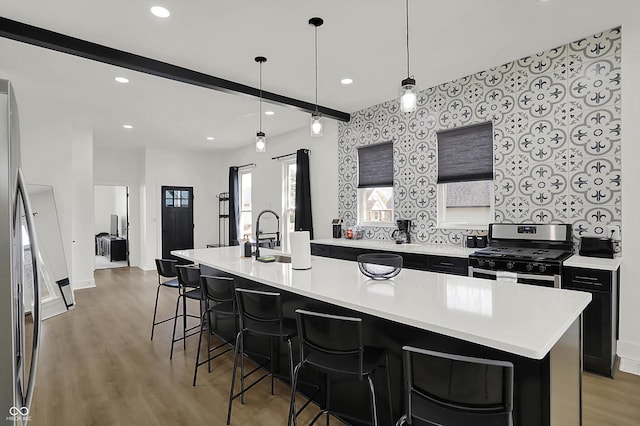 1818 Orleans St, Indianapolis, IN 46203 - kitchen featuring a kitchen bar, appliances with stainless steel finishes, light countertops, light wood-style floors, and dark cabinetry