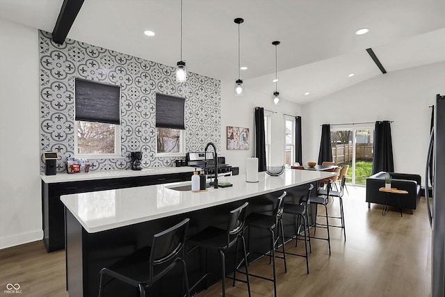 1818 Orleans St, Indianapolis, IN 46203 - kitchen with light wood-type flooring, light countertops, dark cabinets, a sink, and vaulted ceiling
