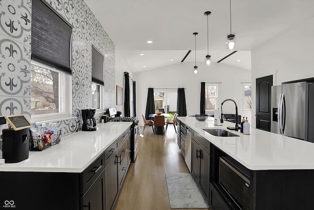 1818 Orleans St, Indianapolis, IN 46203 - kitchen with vaulted ceiling, a sink, dark cabinets, stainless steel appliances, and light wood-style flooring
