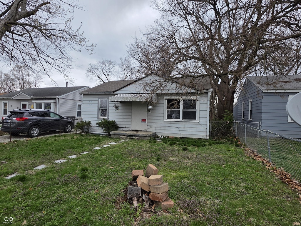 5842 Greenfield Ave, Indianapolis, IN 46219 - bungalow-style home with fence, roof with shingles, and a front lawn