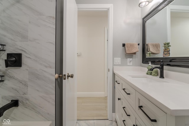 full bathroom featuring baseboards, marble finish floor, vanity, and tiled shower
